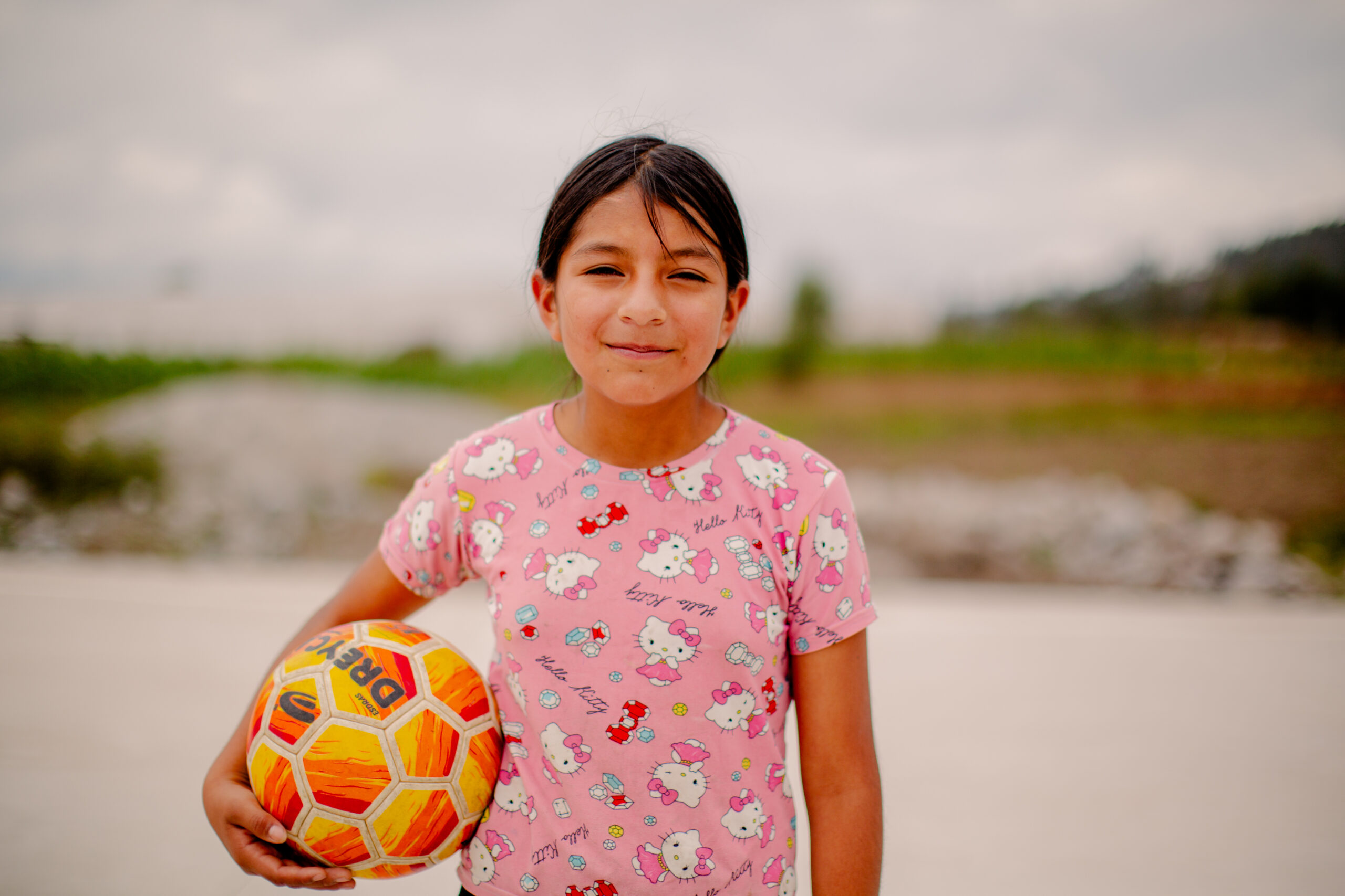 Maya from Ecuador standing and holding a soccer ball.